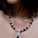 Close-up of a handmade pastel crystal charm necklace with white pearl accents and a playful vintage-inspired pendant.