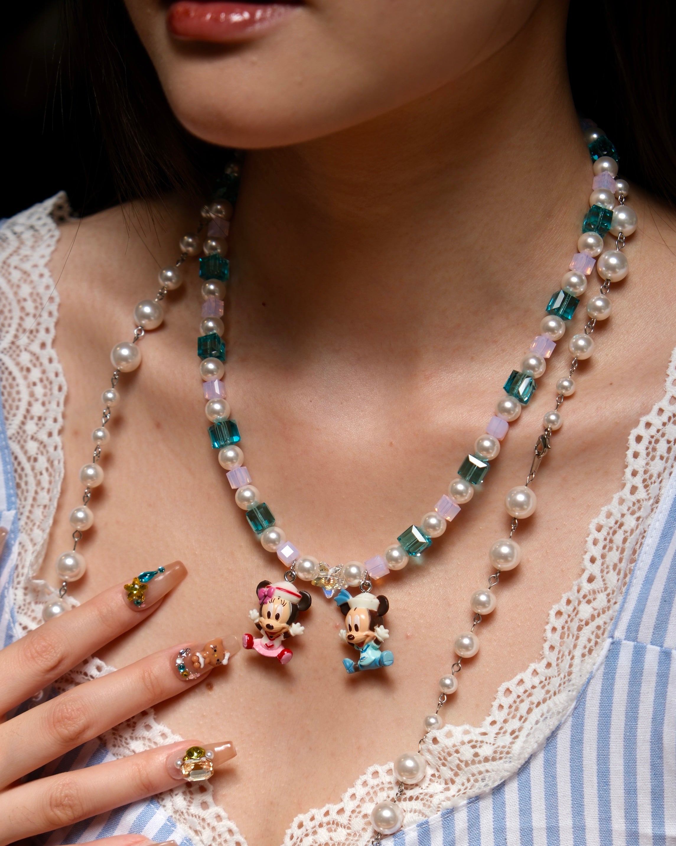 Close-up of a handmade pastel Swarovski crystal charm necklace with pink and blue beads, pearl accents, and nostalgic collectible charms.