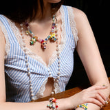 Studio product photo of a handmade purple and black Swarovski crystal charm necklace with white pearl accents and a nostalgic collectible pendant.