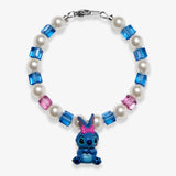 Studio product photo of a handmade blue bow character-inspired charm bracelet with white Swarovski pearls and blue-pink crystal beads.