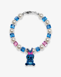 Studio product photo of a handmade blue bow character-inspired charm bracelet with white Swarovski pearls and blue-pink crystal beads.