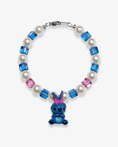 Studio product photo of a handmade blue bow character-inspired charm bracelet with white Swarovski pearls and blue-pink crystal beads.