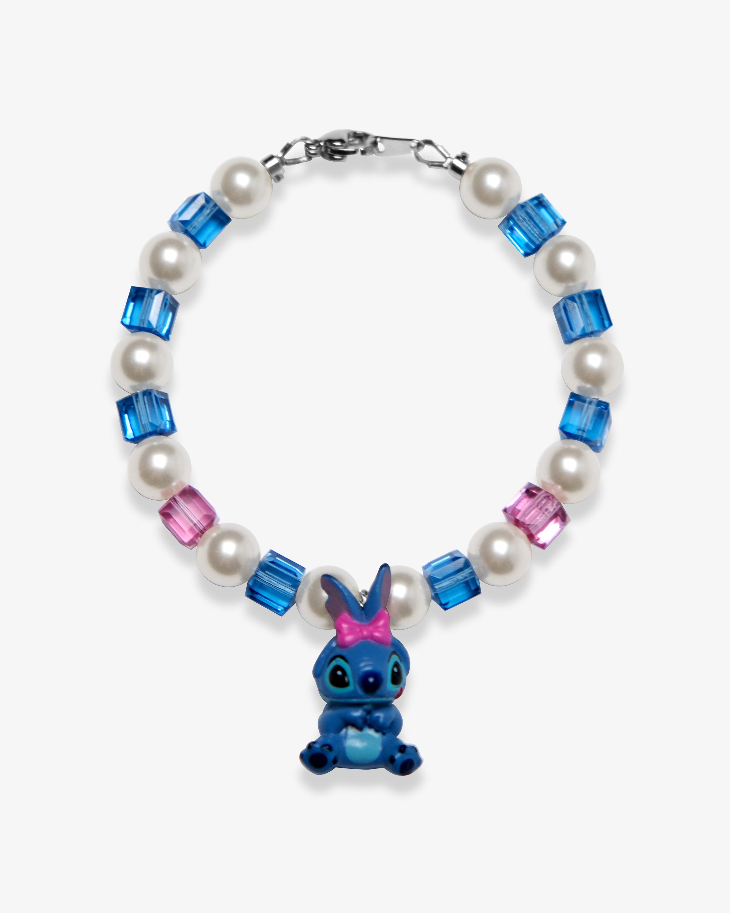 Studio product photo of a handmade blue bow character-inspired charm bracelet with white Swarovski pearls and blue-pink crystal beads.