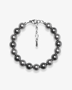 Studio product photo of a handmade charcoal gray Swarovski pearl bracelet with a silver clasp and adjustable extender chain.