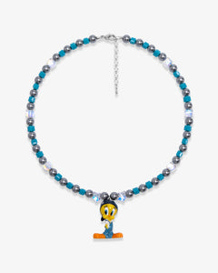 Studio product photo showing Blue and charcoal Swarovski crystal pearl charm necklace with a vintage yellow bird-inspired pendant.