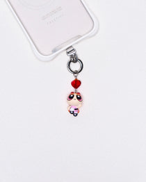Product photo showing Pink character-inspired phone charm with a red crystal heart and silver-tone phone hardware.