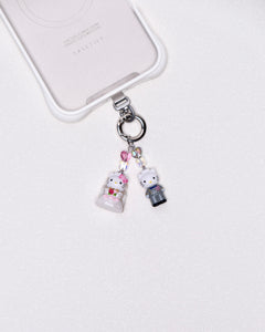 Product photo showing Vintage character-inspired phone charm with pink and gray figures, crystal accents, and silver-tone phone hardware.