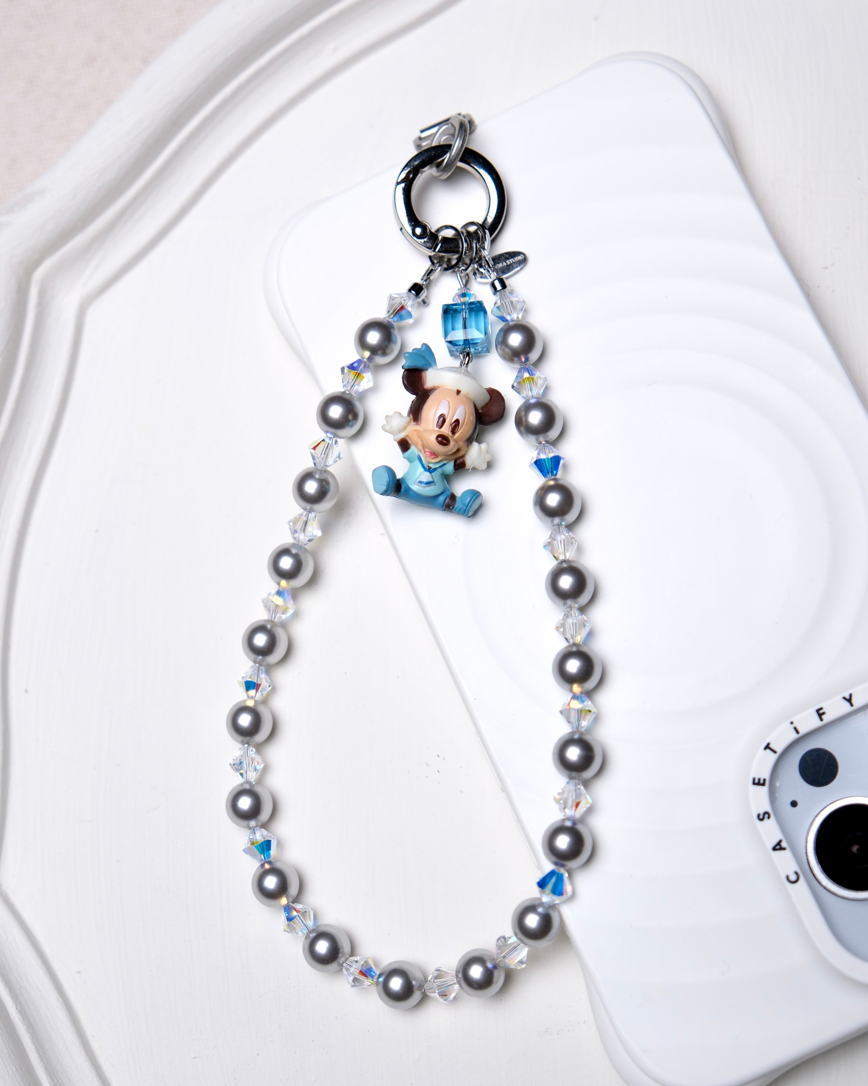 Detail product photo of a gray Swarovski pearl phone chain with white crystal accents.