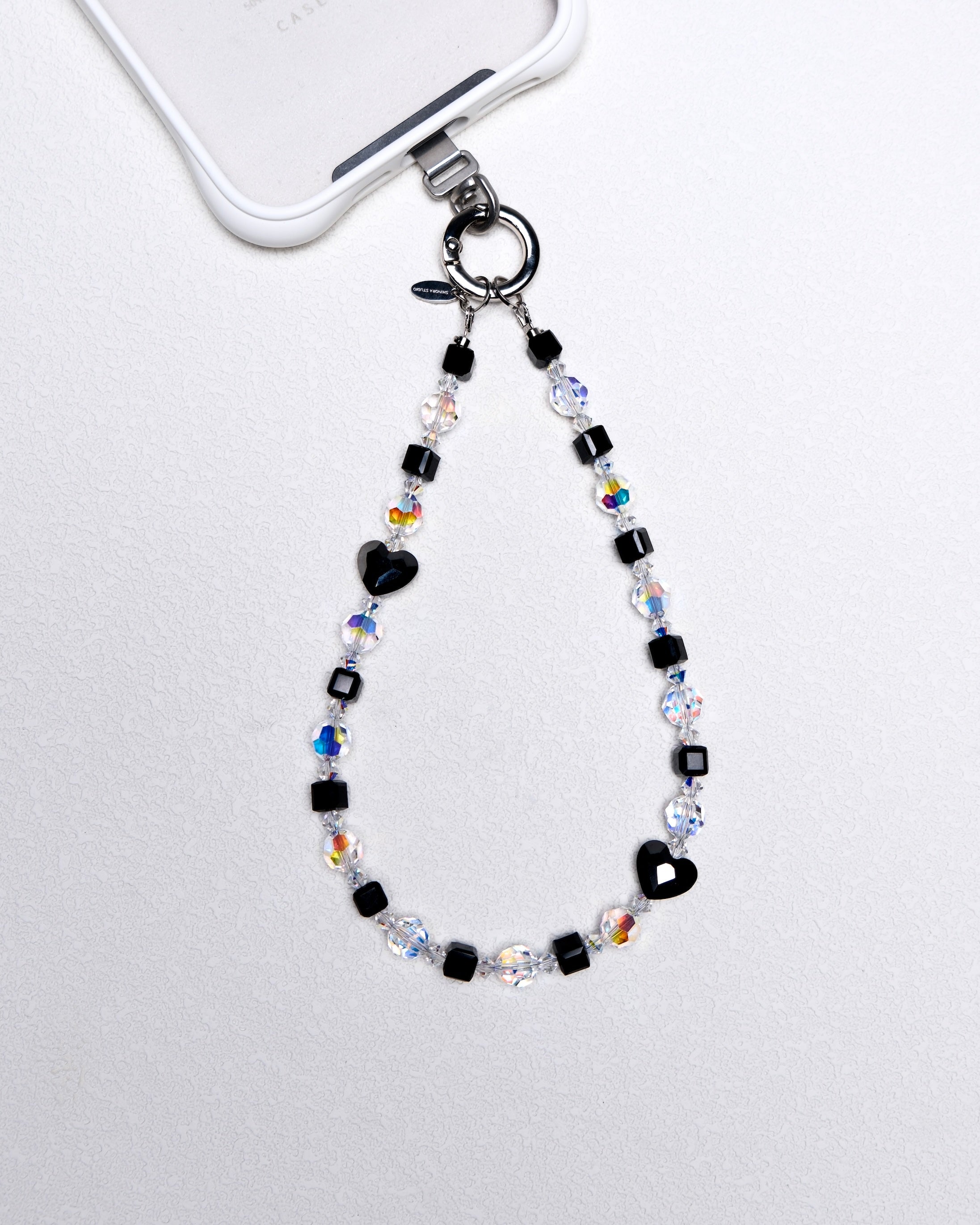 Product photo of a black Swarovski crystal phone chain with clear and iridescent crystal details.