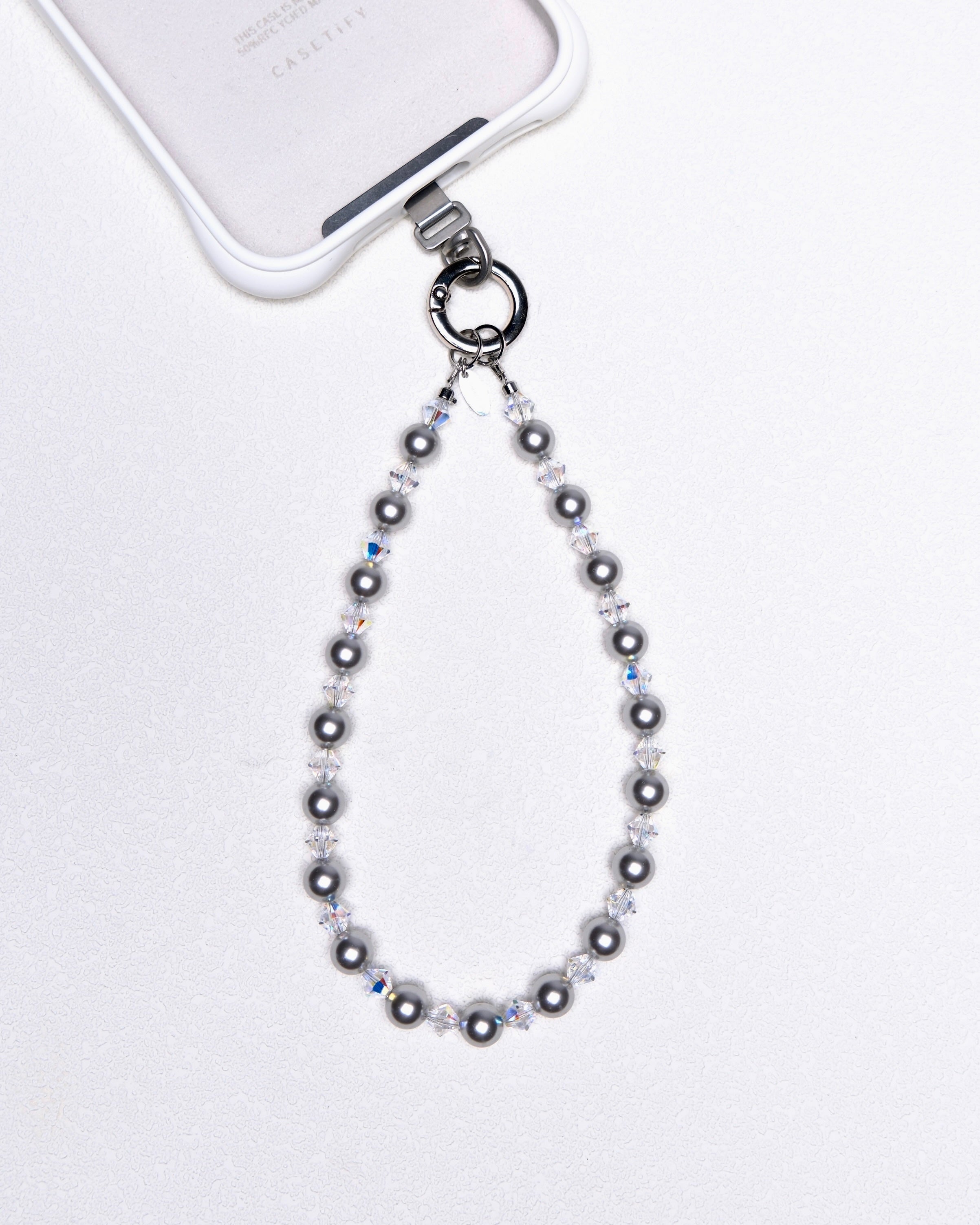 Product photo of a gray Swarovski pearl phone chain with white crystal accents.