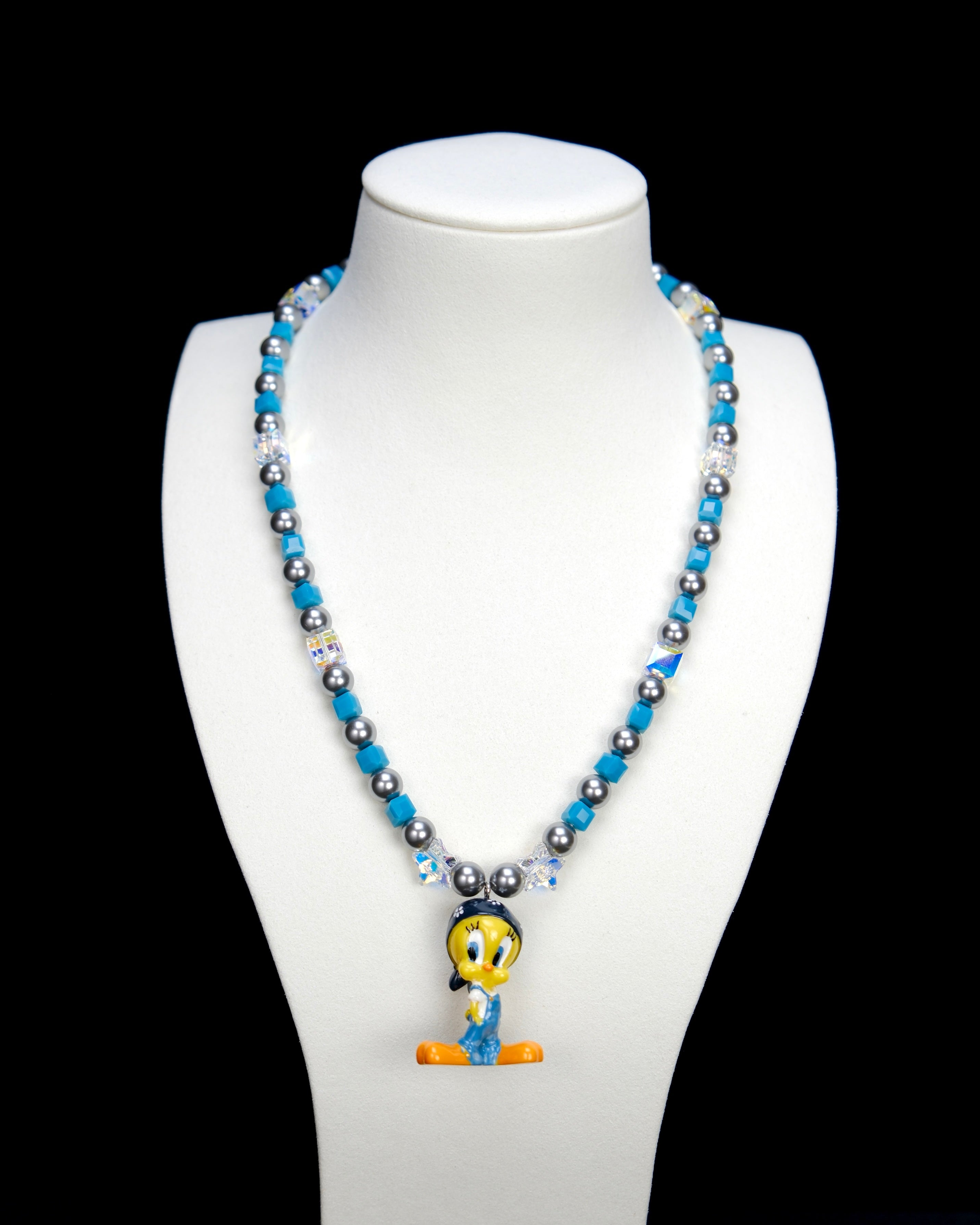 Additional product photo of a blue crystal and charcoal pearl charm necklace with a vintage yellow character charm.