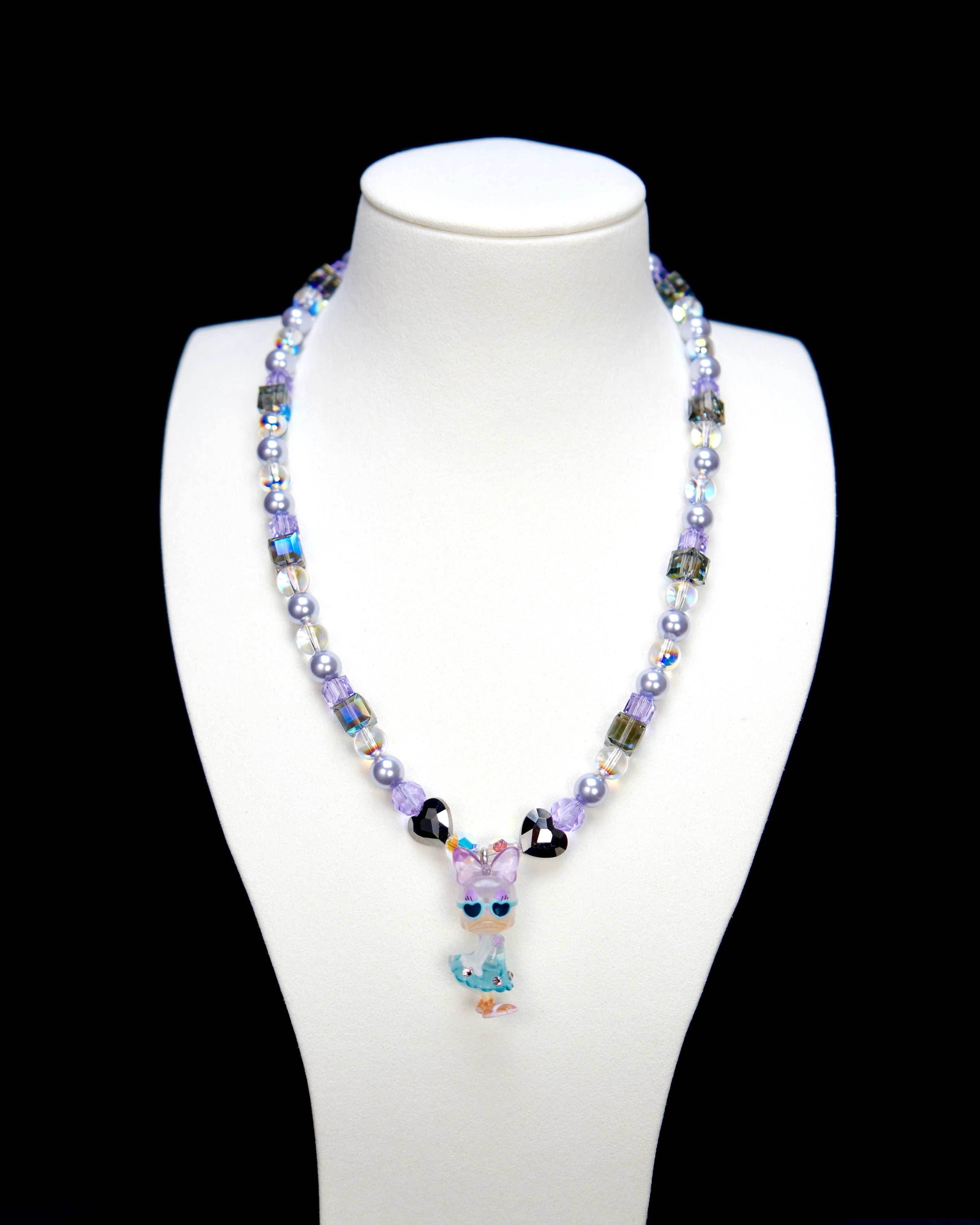 Detail product photo of a lavender and blue duck charm necklace with pearl and iridescent crystal beads.