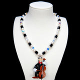 Product photo of a cello-player vintage charm necklace with Swarovski crystals and pearls.