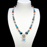 Detail product photo of an orange and blue duck charm necklace with gray pearls and faceted crystal beads.