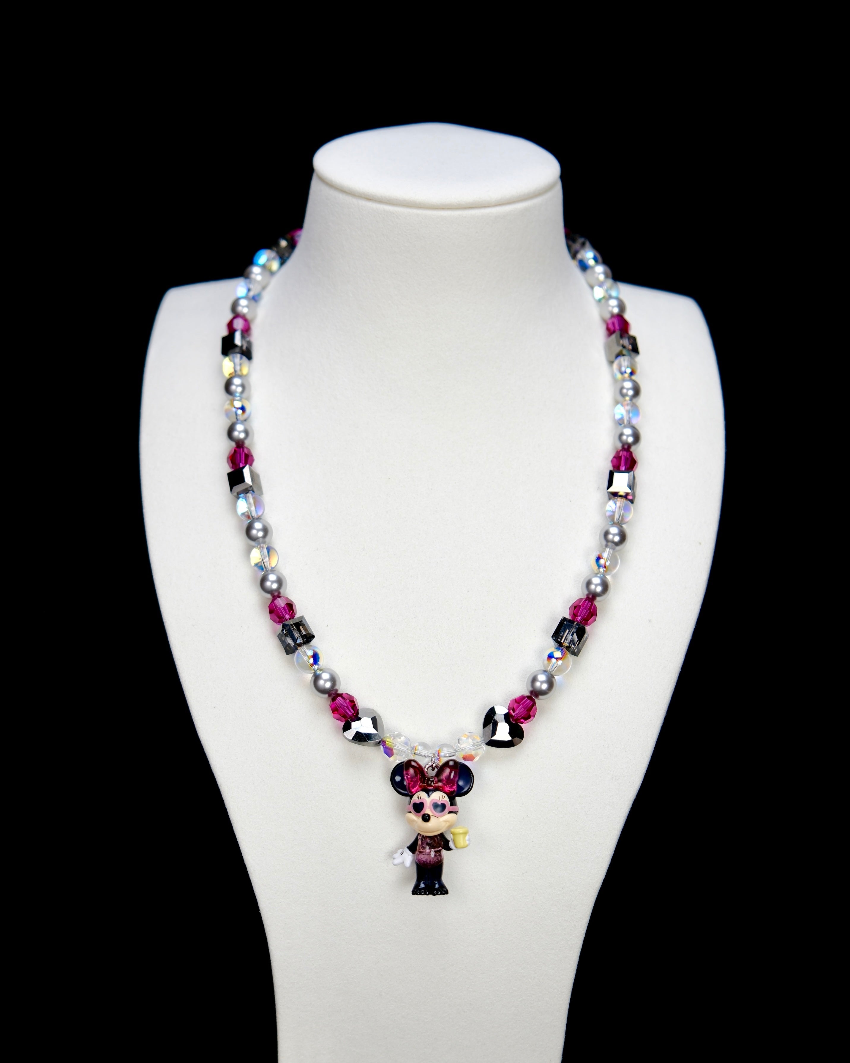 Detail product photo of a pink and silver mouse charm necklace with gray pearls and pink crystal beads.