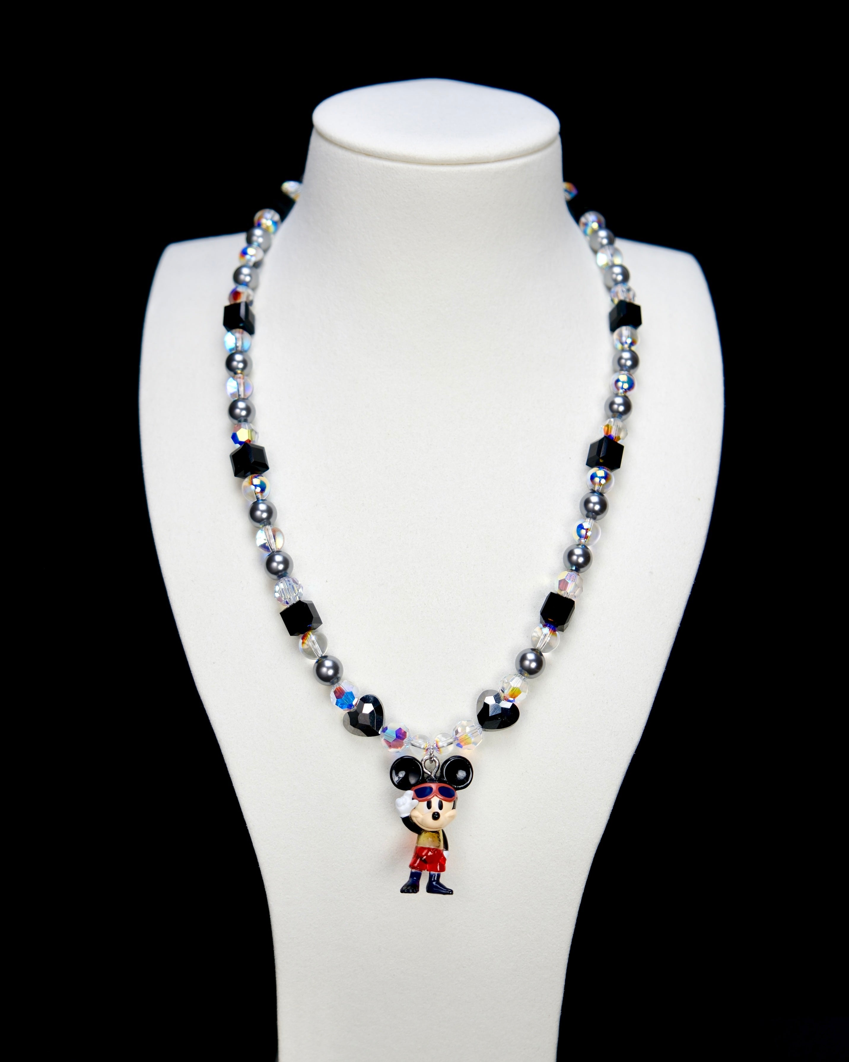 Detail product photo of a black and silver mouse charm necklace with gray pearls and black crystal beads.