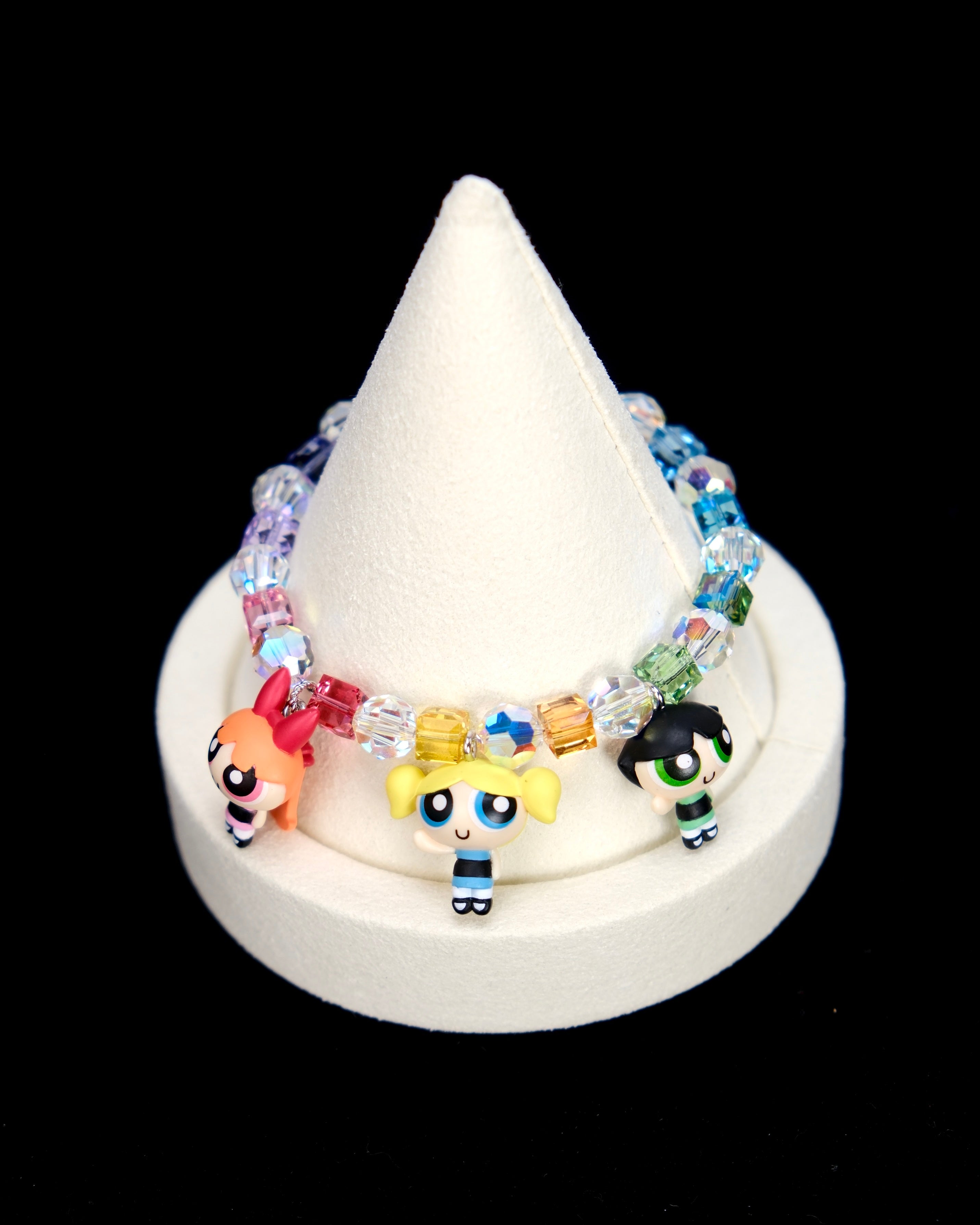 Detail product photo of a rainbow crystal charm bracelet with three vintage heroine character charms.
