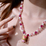 Additional product photo of a pink pearl cat charm necklace with white pearls, pink crystals, and gold-tone hardware.