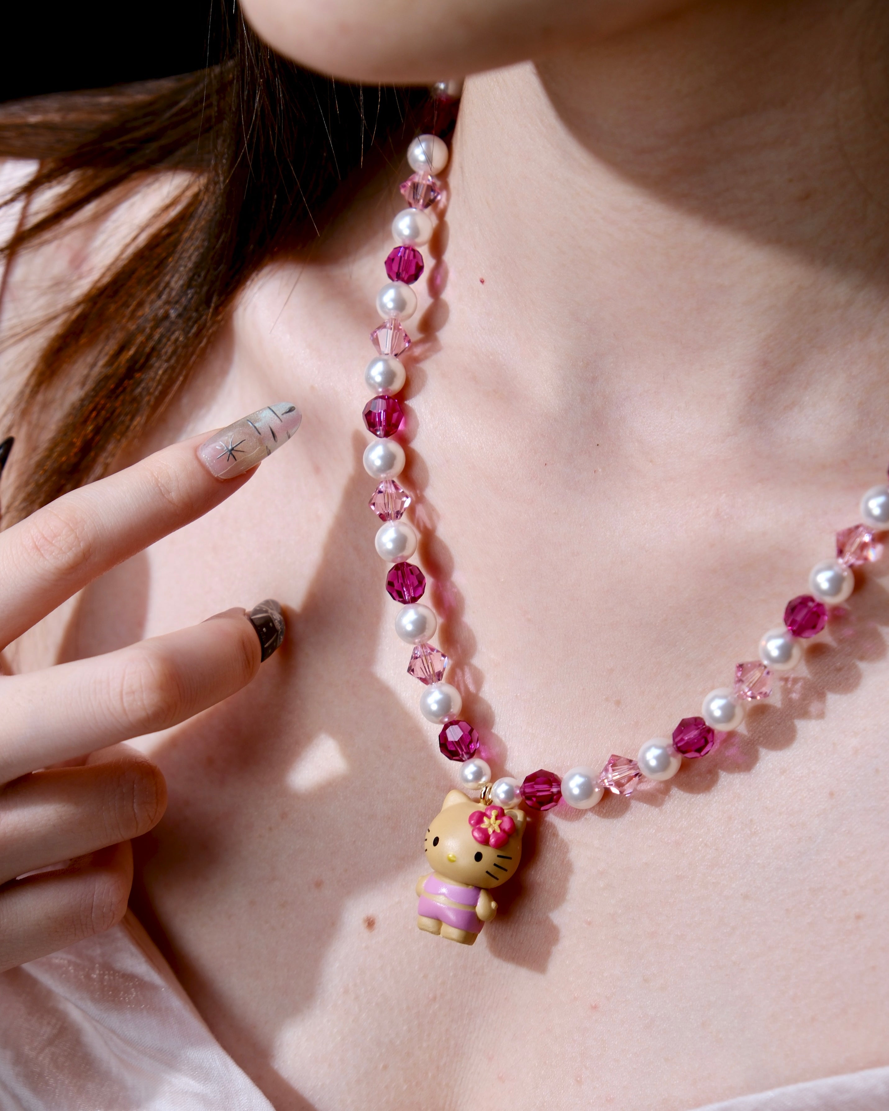 Additional product photo of a pink pearl cat charm necklace with white pearls, pink crystals, and gold-tone hardware.