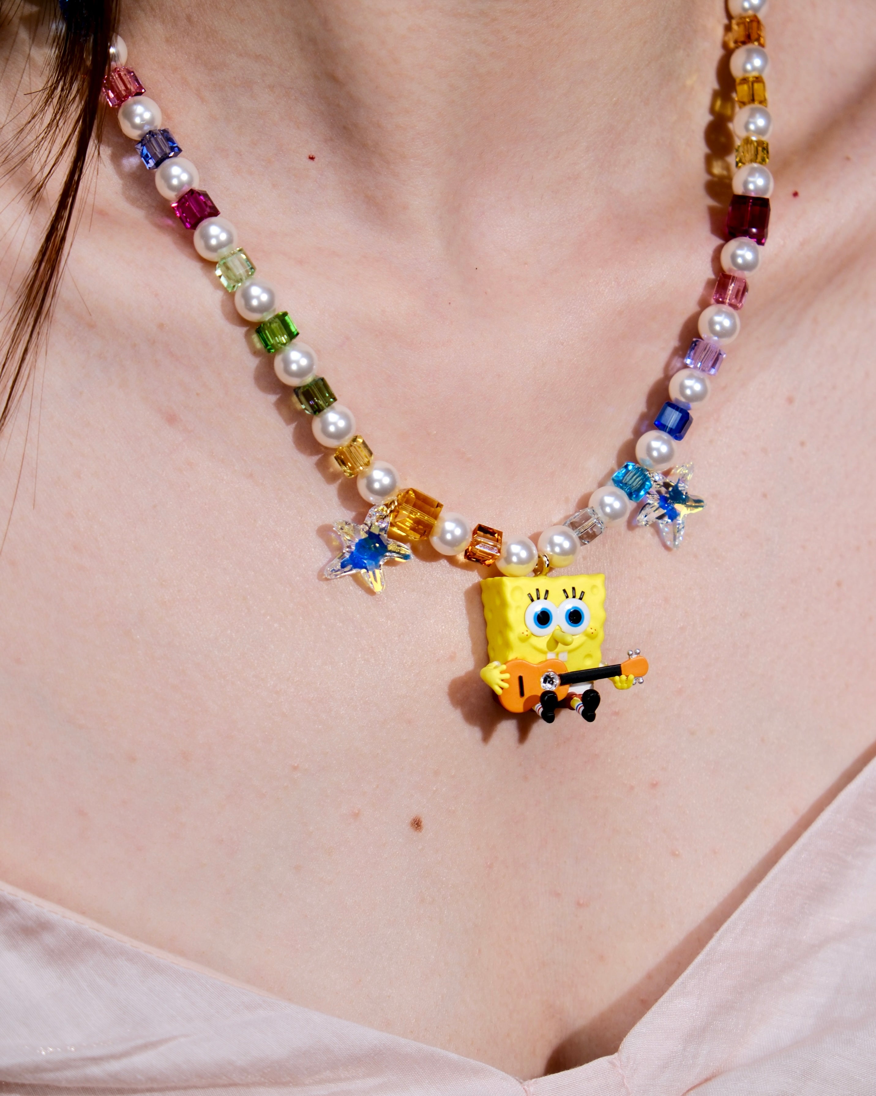 Product photo of a rainbow crystal and pearl guitar charm necklace with blue crystal star accents.