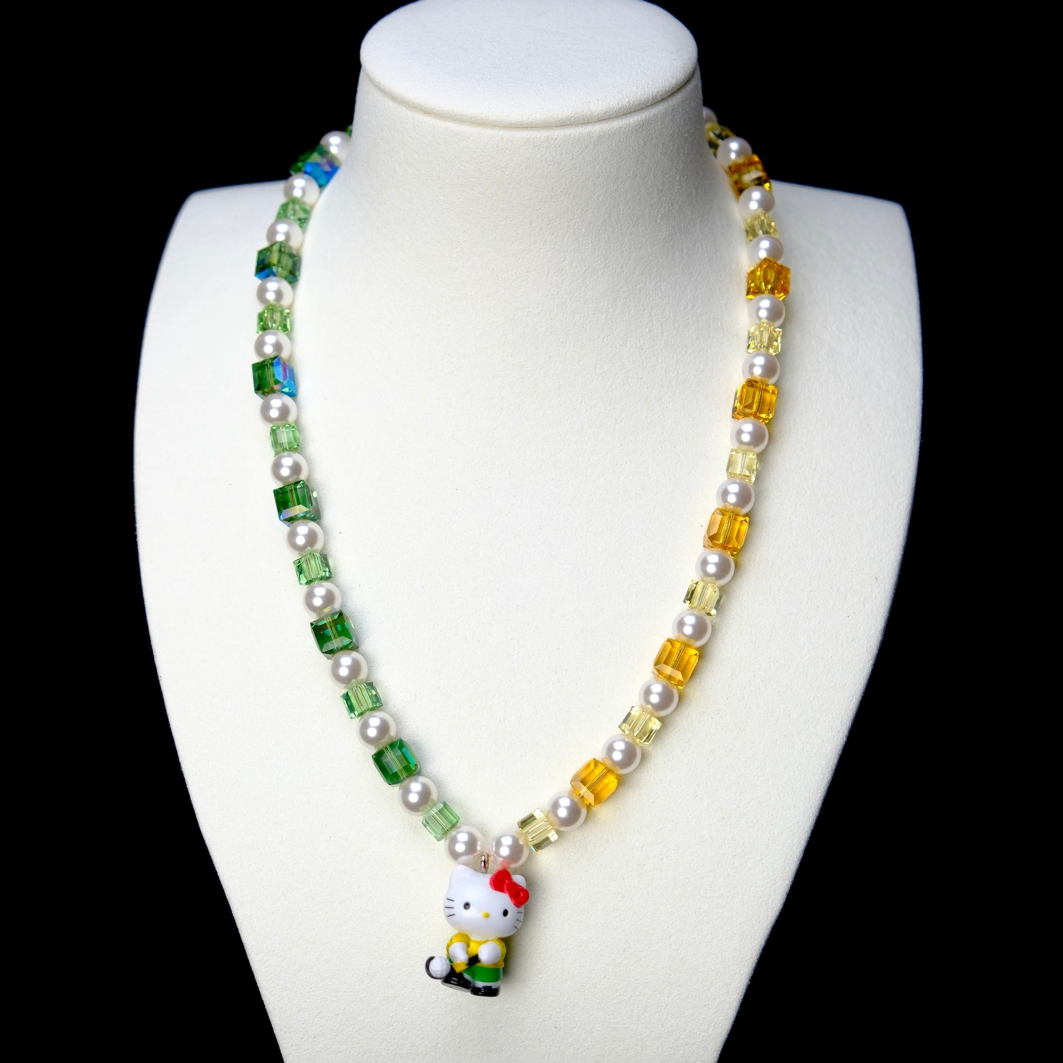 Front studio product view of Green Fairway Crystal Charm Necklace on a white jewelry display against a black background.