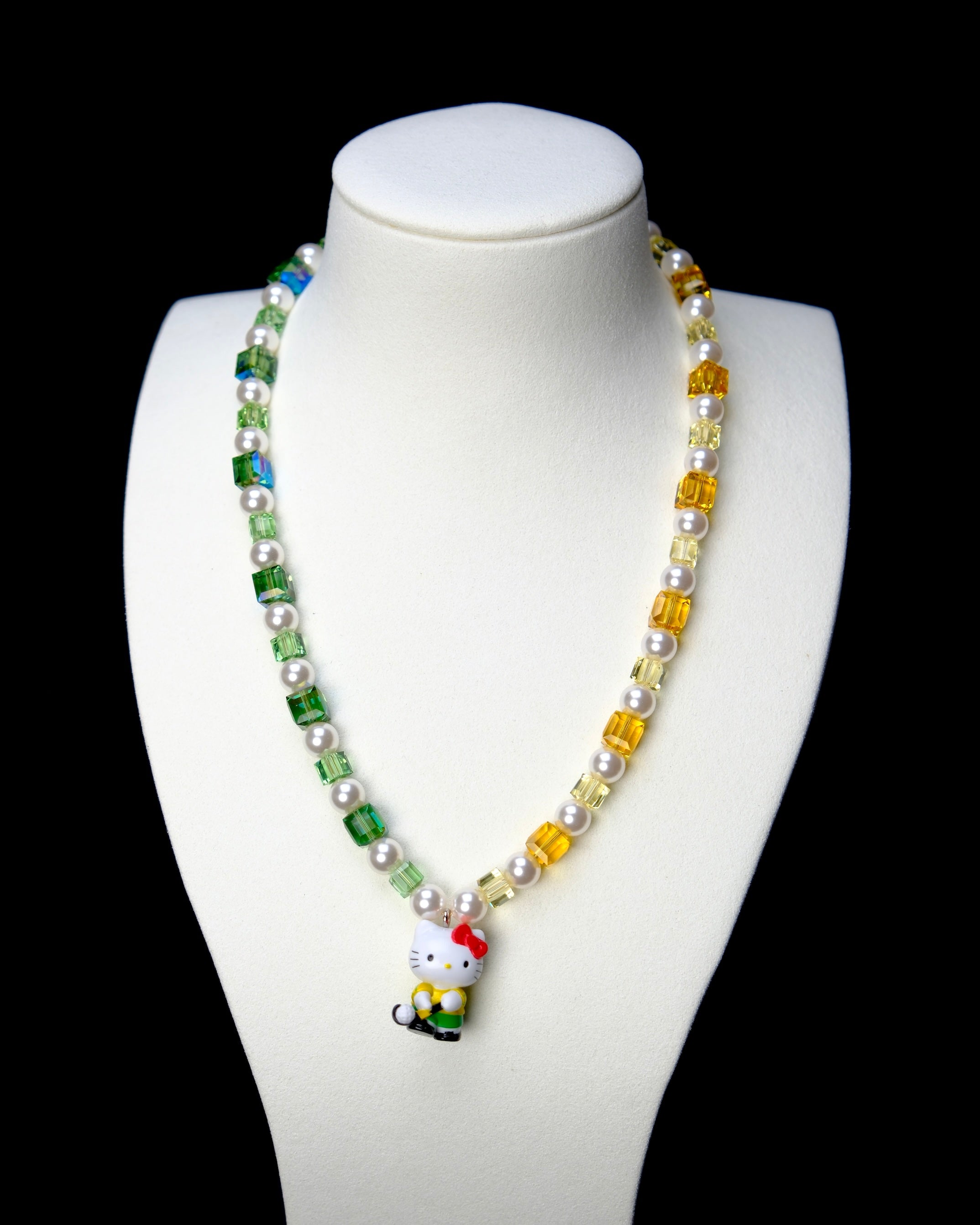 Front studio product view of Green Fairway Crystal Charm Necklace on a white jewelry display against a black background.