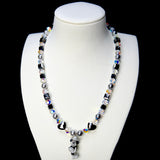 Front studio product view of Midnight Magic Crystal Charm Necklace on a white jewelry display against a black background.
