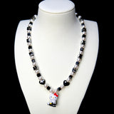 Front studio product view of Noir Court Crystal Charm Necklace on a white jewelry display against a black background.