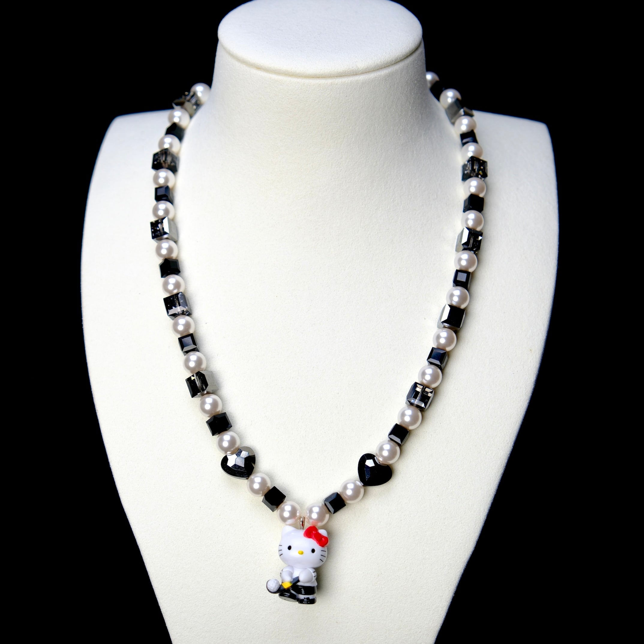 Front studio product view of Noir Court Crystal Charm Necklace on a white jewelry display against a black background.