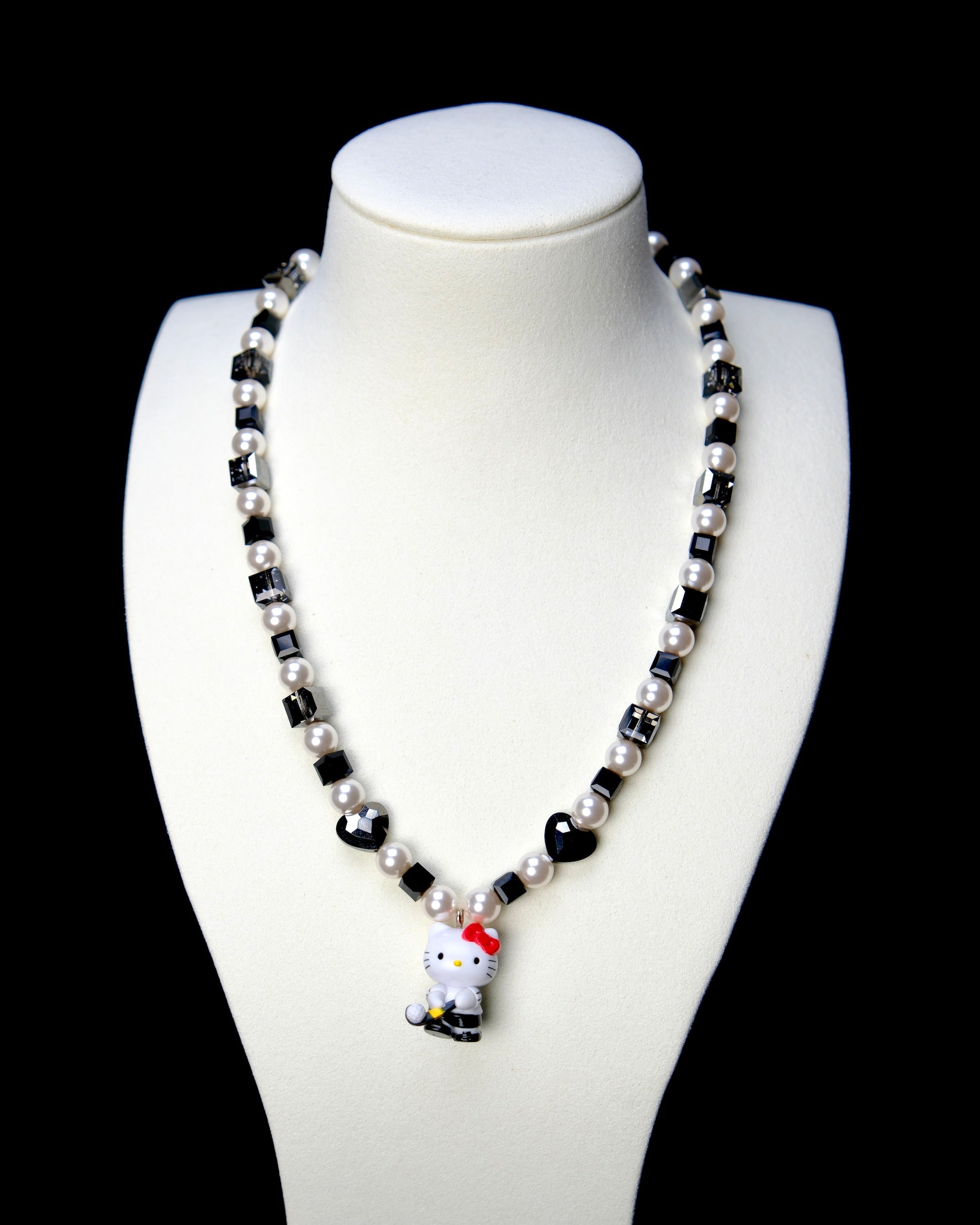 Front studio product view of Noir Court Crystal Charm Necklace on a white jewelry display against a black background.