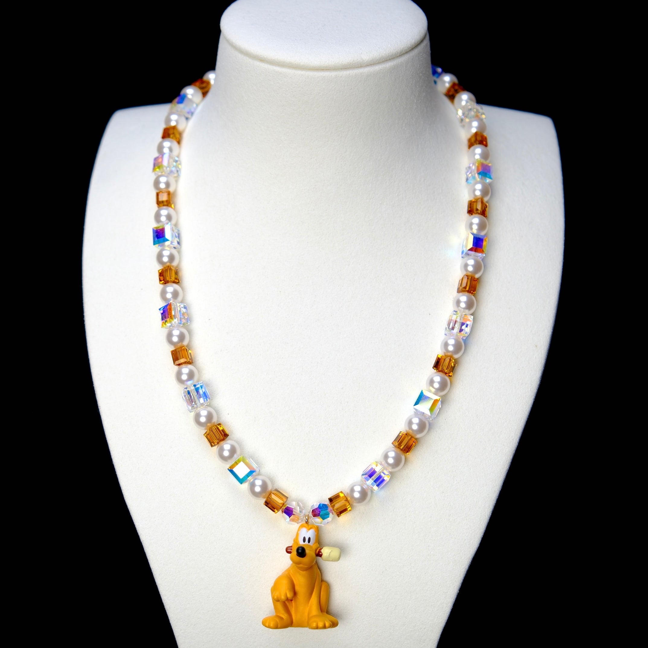 Front studio product view of Amber Daydream Crystal Charm Necklace on a white jewelry display against a black background.