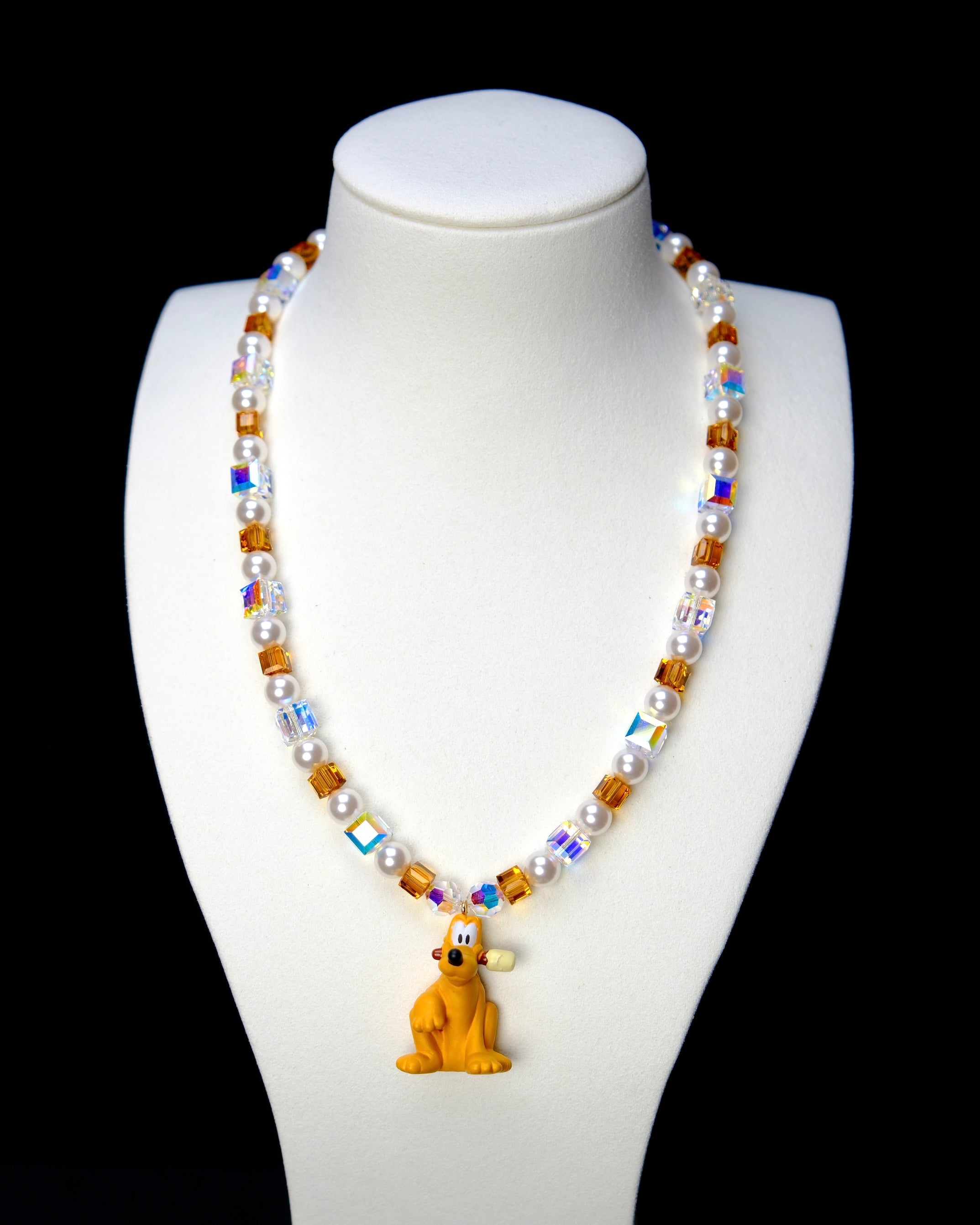 Front studio product view of Amber Daydream Crystal Charm Necklace on a white jewelry display against a black background.