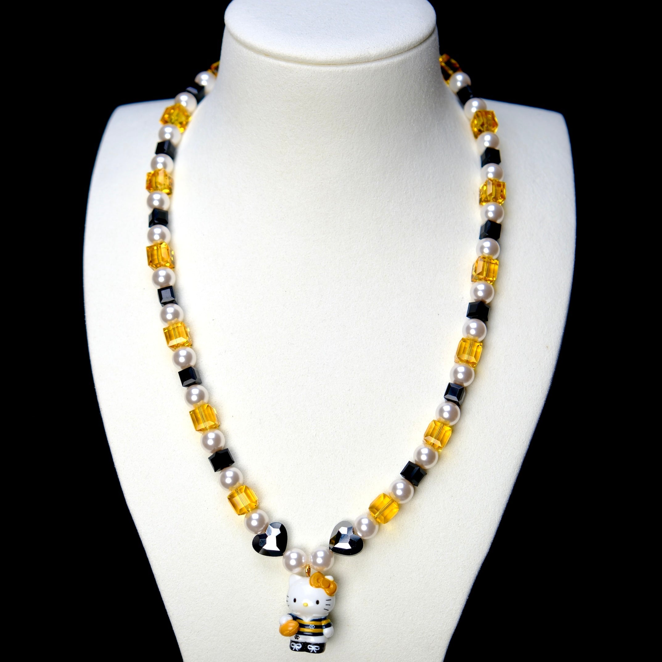Front studio product view of Golden Voyage Crystal Charm Necklace on a white jewelry display against a black background.