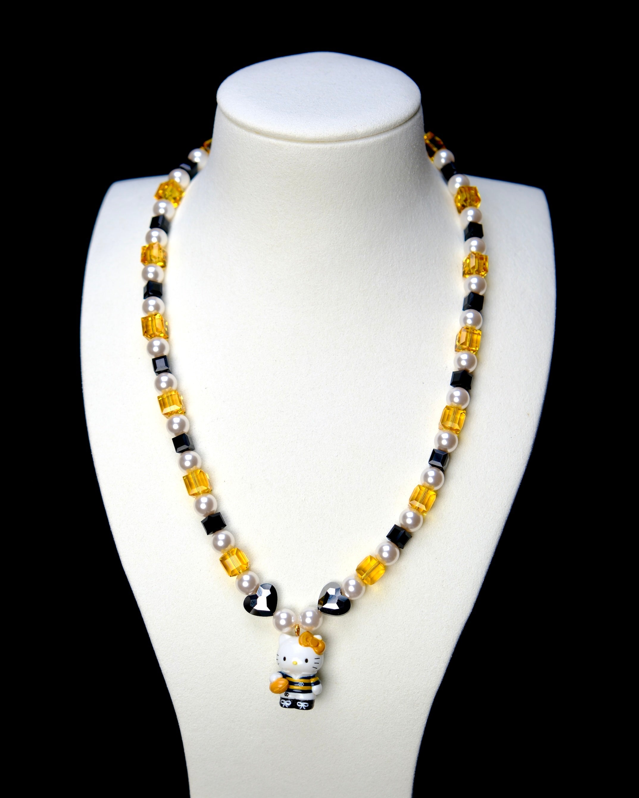 Front studio product view of Golden Voyage Crystal Charm Necklace on a white jewelry display against a black background.