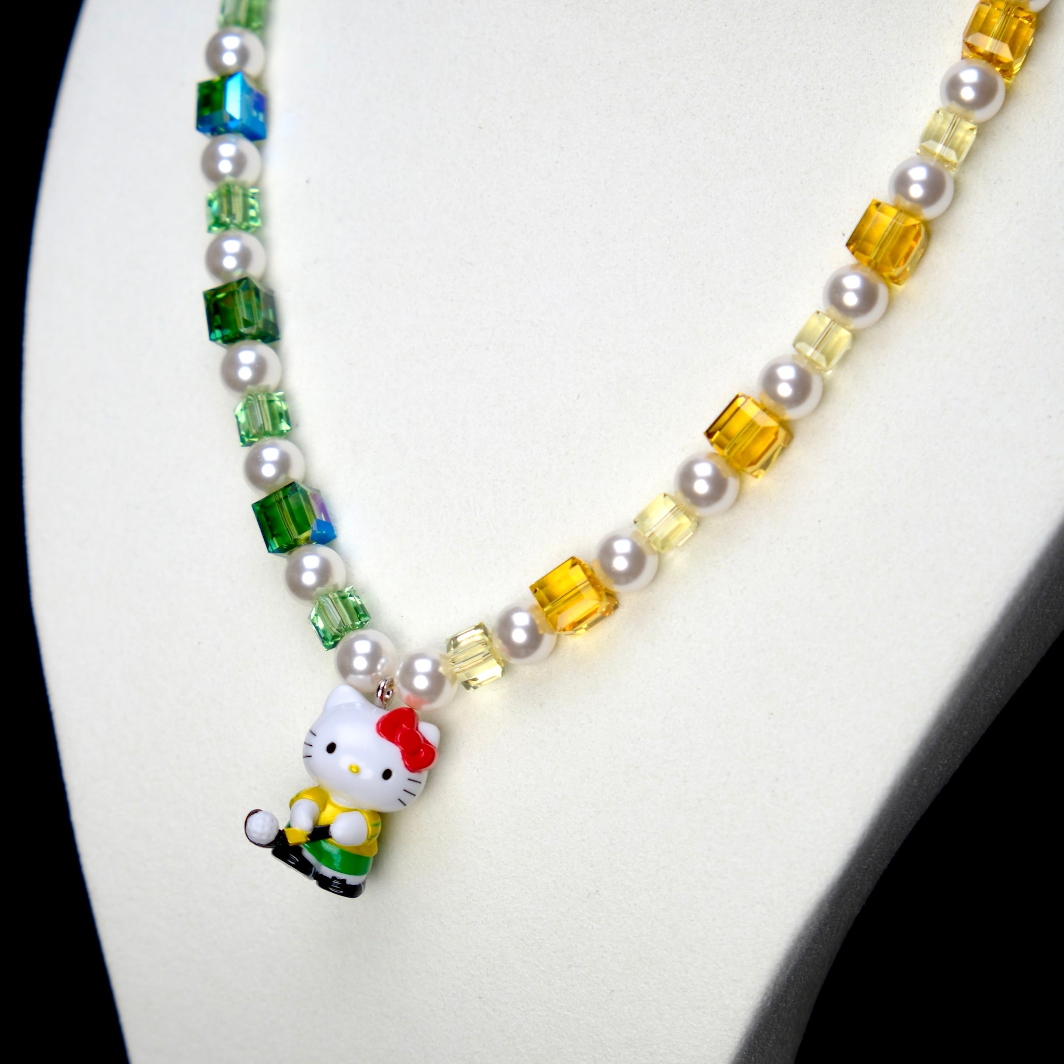 Angled studio product view of Green Fairway Crystal Charm Necklace on a white jewelry display against a black background.