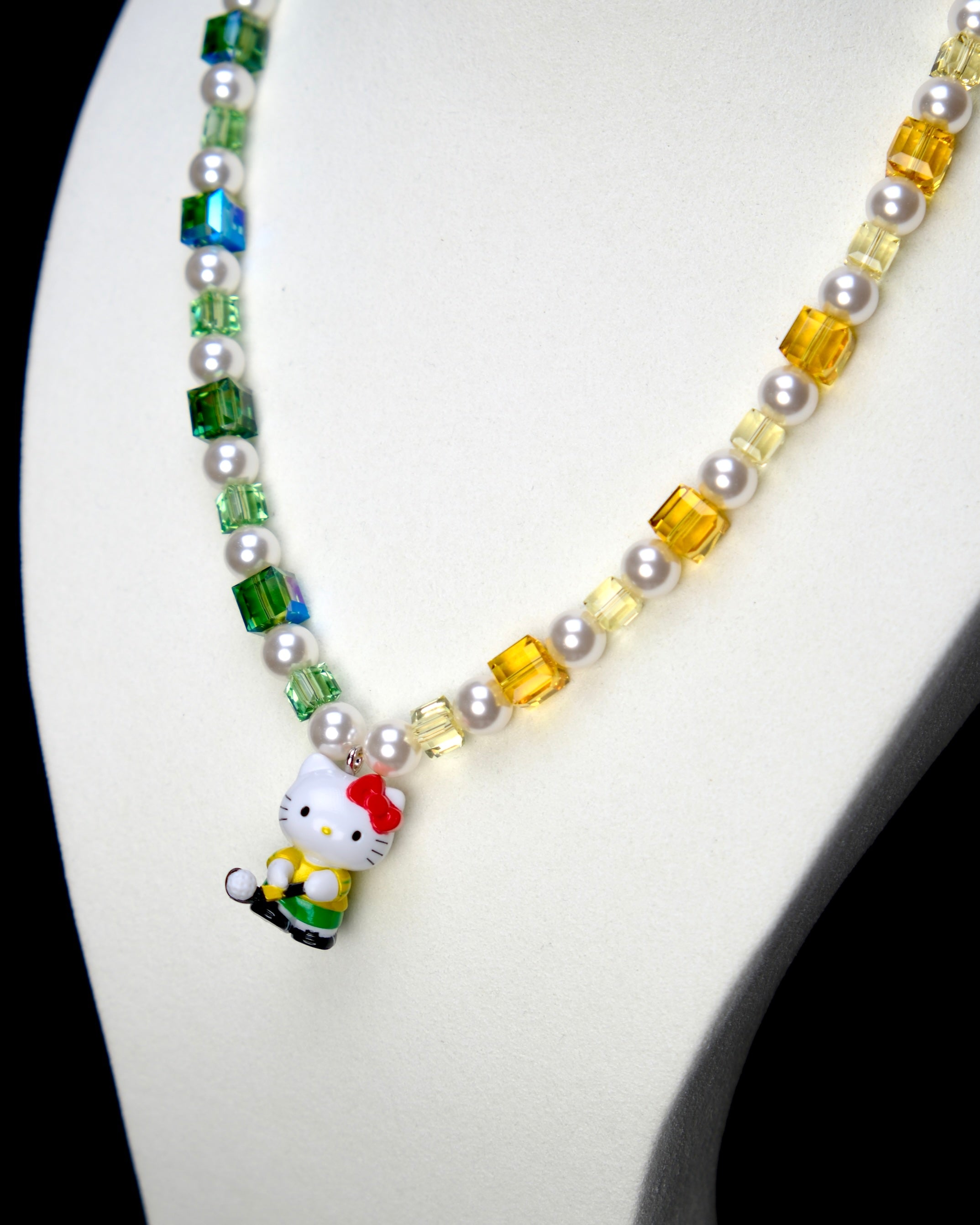 Angled studio product view of Green Fairway Crystal Charm Necklace on a white jewelry display against a black background.