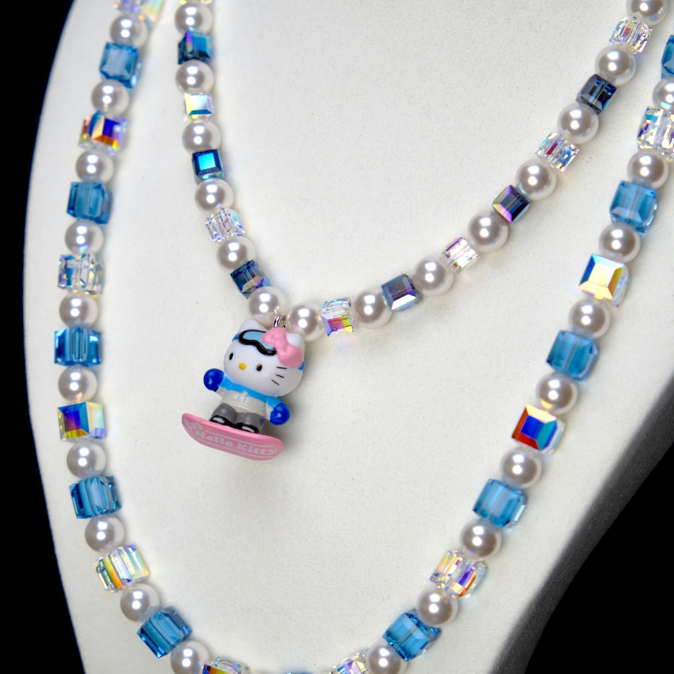 Angled studio product view of Blue Glide Double Layer Crystal Necklace on a white jewelry display against a black background.
