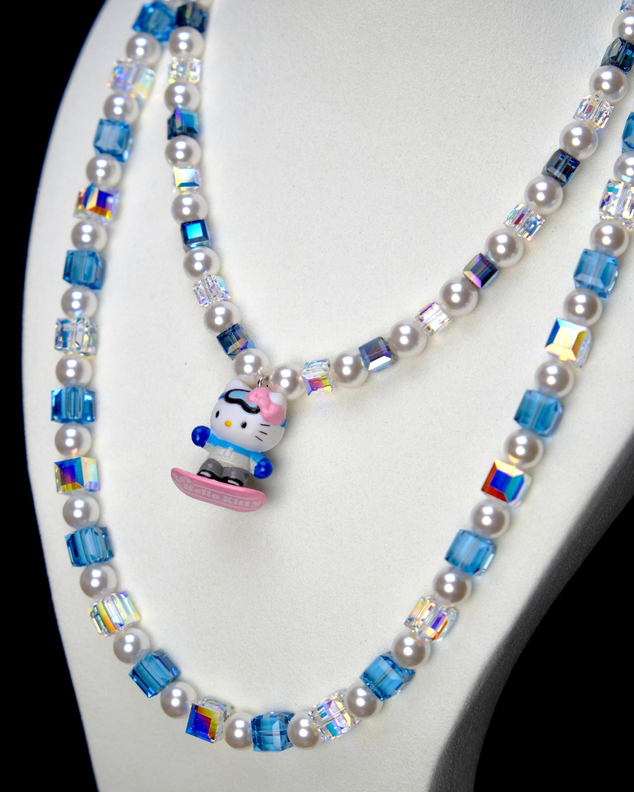 Angled studio product view of Blue Glide Double Layer Crystal Necklace on a white jewelry display against a black background.