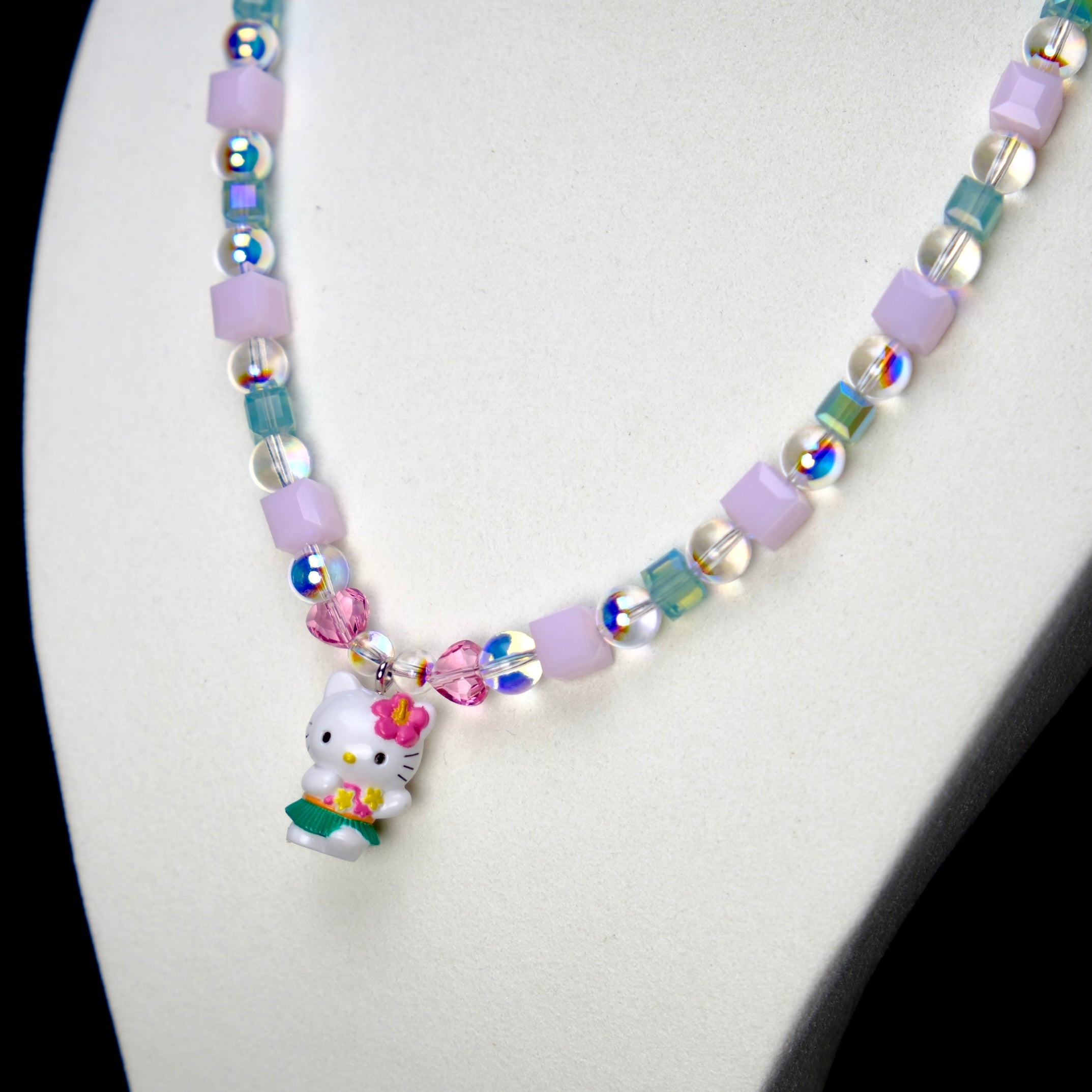 Angled studio product view of Lilac Bloom Crystal Charm Necklace on a white jewelry display against a black background.
