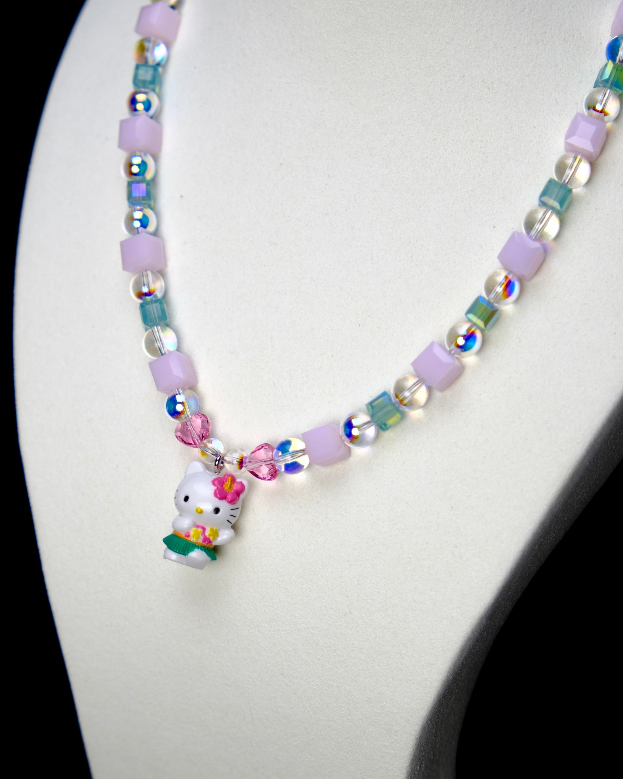 Angled studio product view of Lilac Bloom Crystal Charm Necklace on a white jewelry display against a black background.