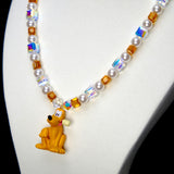 Angled studio product view of Amber Daydream Crystal Charm Necklace on a white jewelry display against a black background.