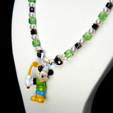 Angled studio product view of Emerald Quest Crystal Charm Necklace on a white jewelry display against a black background.