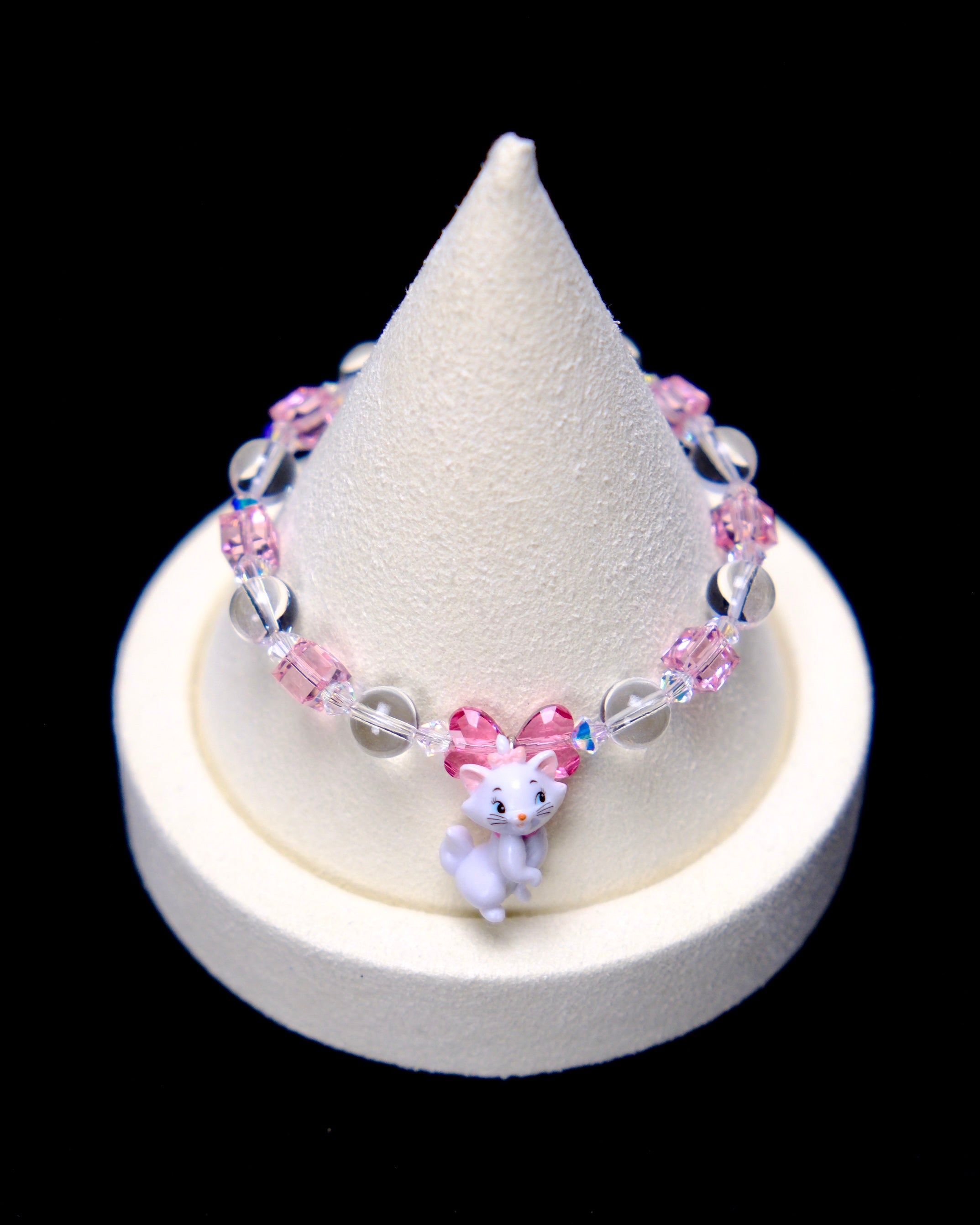 Front studio product view of Pink Bow Crystal Charm Bracelet on a white jewelry display against a black background.