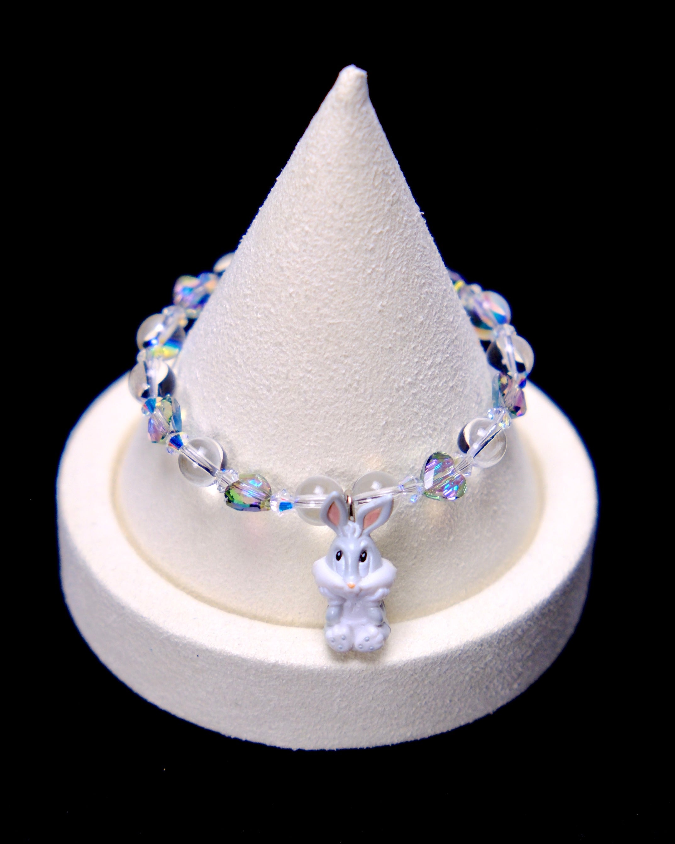 Front studio product view of Iridescent Bunny Crystal Charm Bracelet on a white jewelry display against a black background.