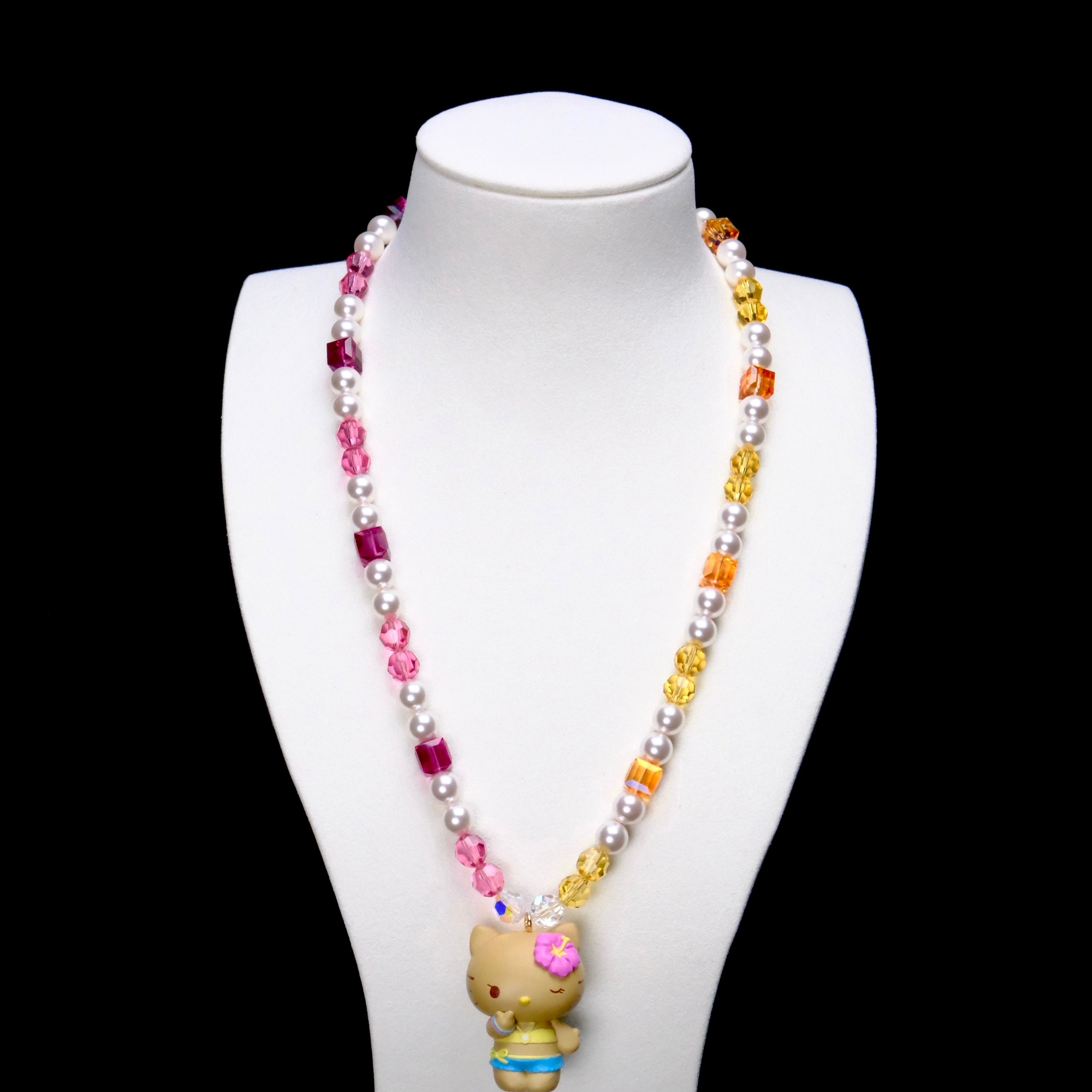Tropical Sunshine Charm Necklace with pink crystals on one side, golden crystals on the other and a cat pendant on a white bust.