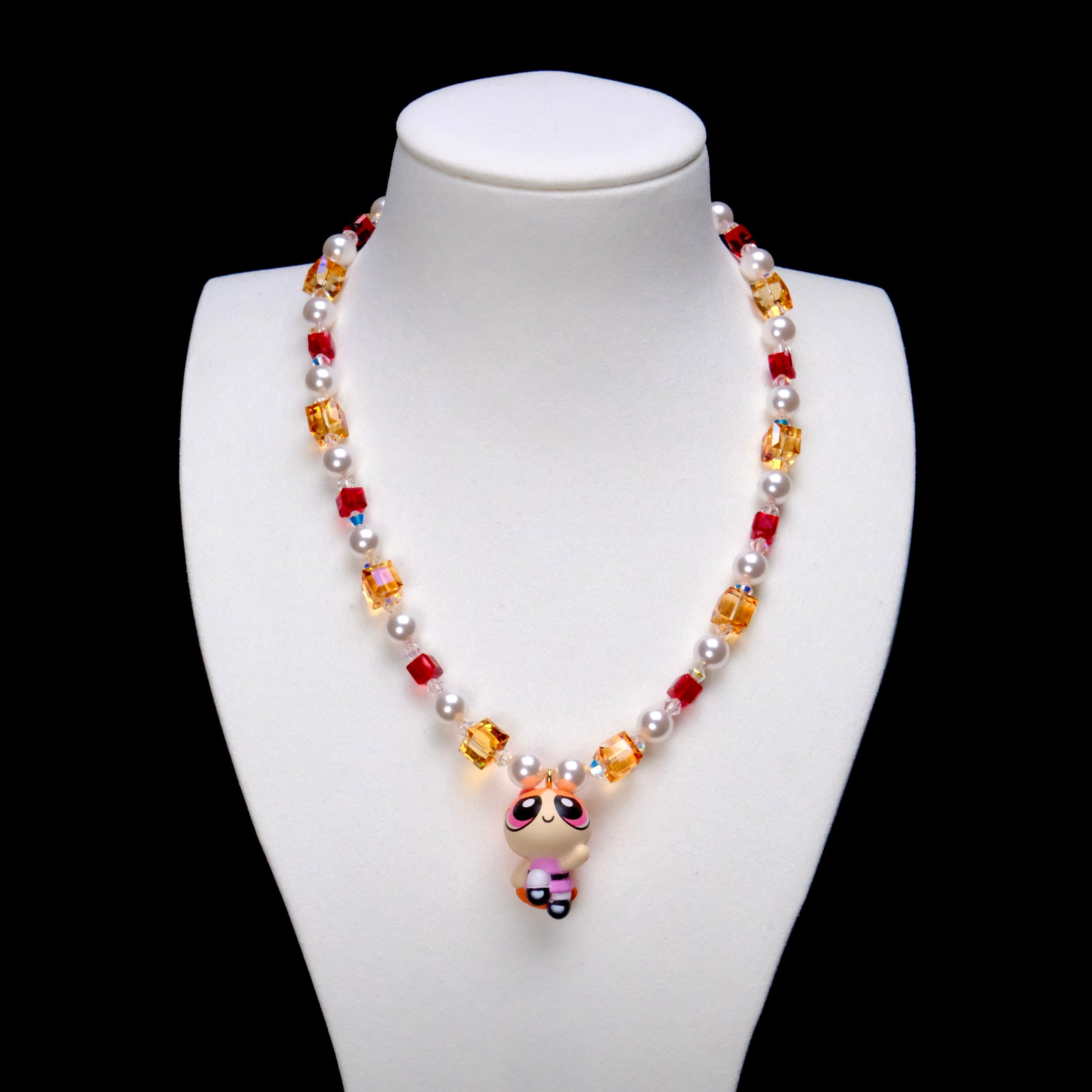 Pink Hero Charm Necklace with red and amber crystal cubes, white pearls and a pink-outfit girl pendant on a white bust.