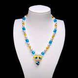 Blue Dreamer Charm Necklace with aqua and golden crystal cubes, white pearls and a blonde girl pendant on a white bust.