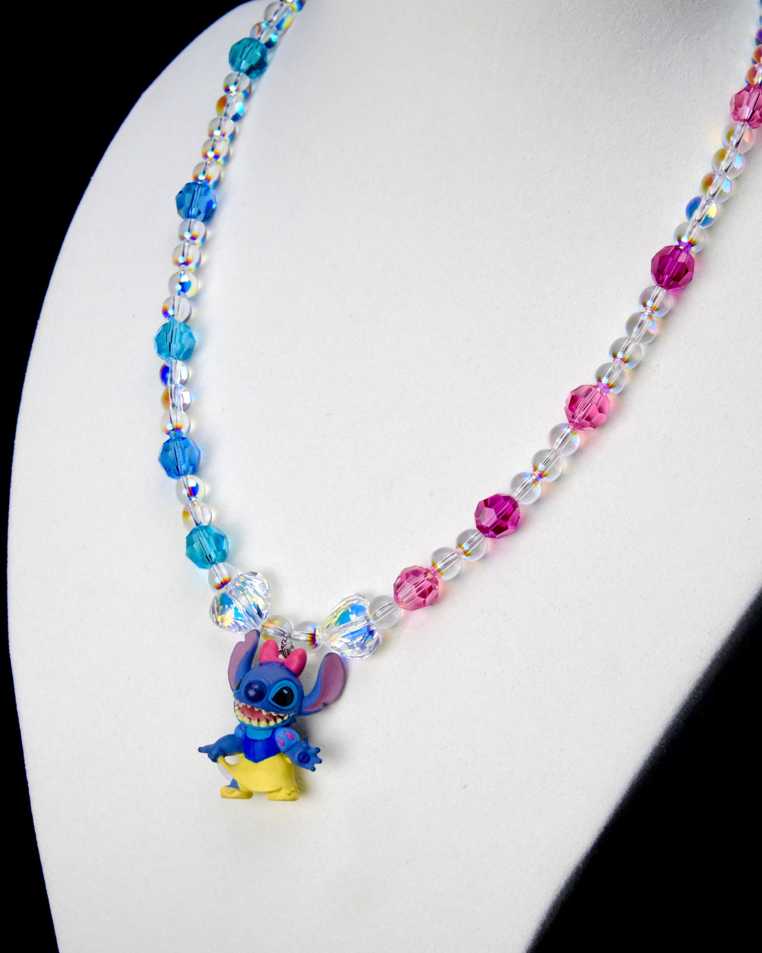 Angled close-up of Blue & Pink Fairytale Charm Necklace showing blue and pink crystals and a blue character in a princess outfit.