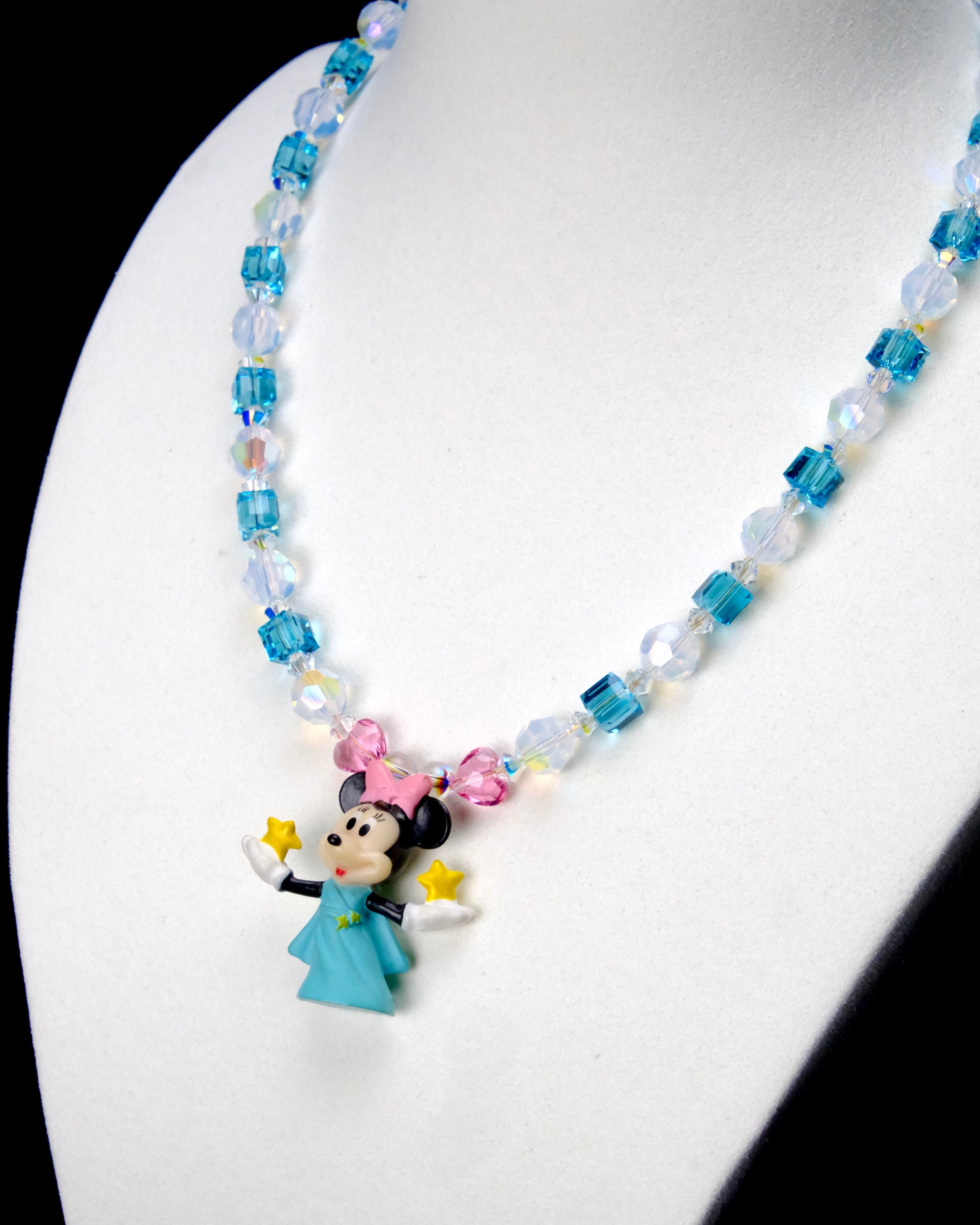 Angled close-up of Aqua Star Wishes Charm Necklace showing aqua crystals, star beads and a pink-bow mouse holding a yellow star.