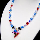 Angled close-up of Blue & Red Board Rider Charm Necklace showing blue and red crystals, black heart beads and a character on a red board.